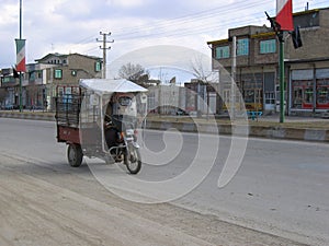 Three-wheeled vehicle rides on an empty road in the city.