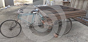 A three wheeler trolly loaded with steel frames for shifting in India, transportation inside construction site.