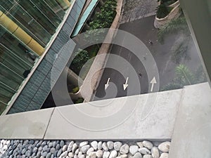 Three white arrows on a street viewed from second floor balcony with decorative stones