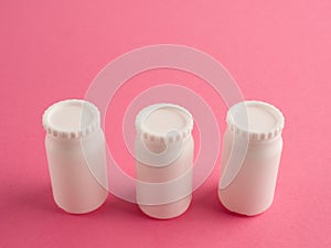 Three white banks with lids on a pink