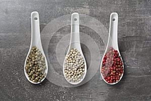 Three white ceramic spoons filled with various peppers