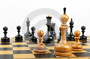 Three white chess pieces opposite the black figures