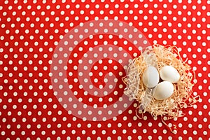 Three white chicken eggs on a red fabric with polka dots
