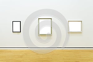 Three white clipped paintings hung on a clear wall.