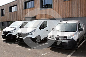 Three White Delivery Trucks vans Backed Up to Warehouse Building