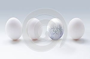 Three white eggs and glassy egg with water bubbles and biohazard sign