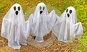 three white ghosts as seasonal decorations in Autumn for Halloween