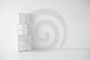 Three white gift boxes packages with ribbons on table