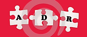 Three white jigsaw puzzles with the text ADR Alternative Dispute Resolution on a bright red background