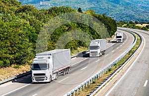 Three white Lorry trucks in line on a country highway