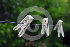 Three white plastic simple normal clothespins on a black rope on