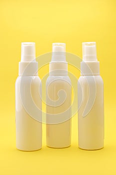 White Plastic Bottles with Spray Caps on a Bright Yellow Background