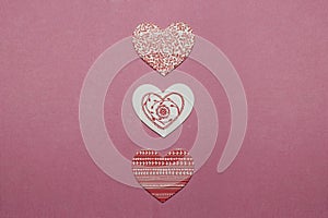 Three white and red heart-shaped decorations on pink background. Valentine`s Day greeting card.