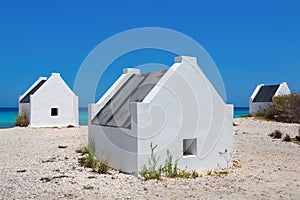 Three white slave houses on beach near sea