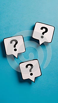 Three white speech bubbles with black question marks on bright blue