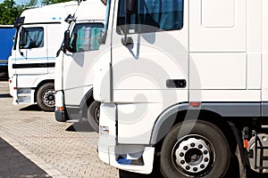 Three white trucks on parking