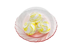 Three white and yellow zefir on a pink glass dish