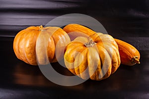 Three whole fresh orange big pumpkin on black background, closeup. Organic agricultural product, ingredients for cooking