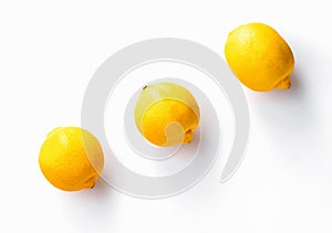 Three whole  lemons diagonally on white background