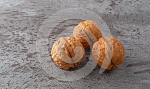 Three whole walnuts on a gray background