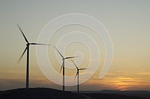 Three wind power aerogenerators skyline at dusk