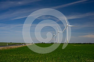 Three wind turbines on green fields against a blue sky