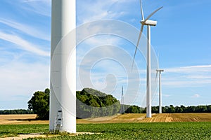Three wind turbines lined up amid the fields