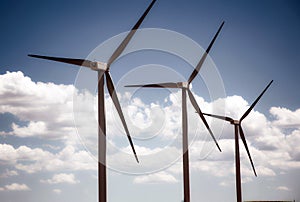 Three wind turbines in nearly perfect sequence against a cloudy blue sky