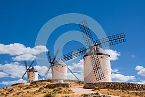 Three of windmills of Consuegra on the hill with blue sky and white clouds (Spain