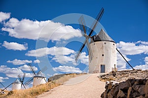 Three of windmills of Consuegra on the hill with blue sky and white clouds (Spain