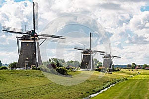 Three windmills of `Driemolengang Leidschendam` under a beautiful clouded sky photo
