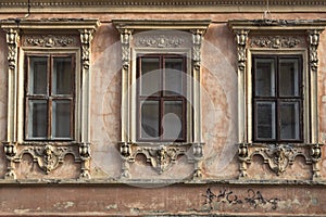 Three windows with carved frames on the facade of the old house