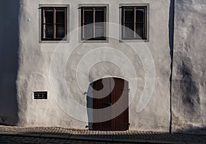 Three windows, a door, a white wall.