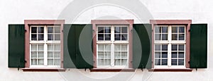 Three windows in a row with dark metal shutters