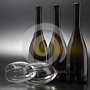 Three wine bottles and two empty wine glasses close up