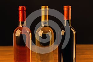 Three wine bottles on wooden table and black background