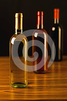 Three wine bottles on wooden table and black background