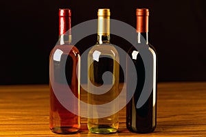 Three wine bottles on wooden table and black background