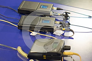 Three wireless microphone transmitter and three wireless microphone reciever on blue table