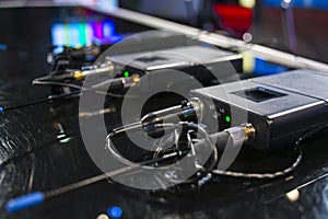 Three wireless microphone transmitter and three wireless microphone reciever on black table in tv studio