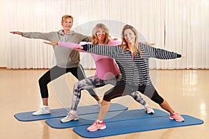 Three woman of different ages doing stretching and power work outs