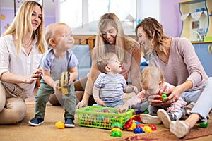 Three woman friends with toddlers playing on the floor in sitting room