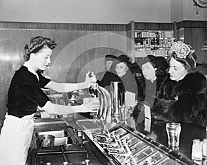 Three woman and a man sitting in a soda fountain