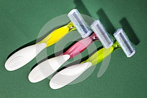 Three women colorful razors with selective focus on a green background.