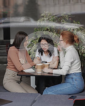 three women comfort each other and help in difficult times. friends talk in a coffee shop and drink tea, moral support