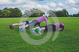 Three women doing push ups in park