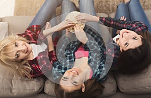 Three women eating popcorn and looking up, top view