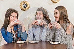 Three women friends enjoy coffee in the cafe. Enjoy coffee while chatting in the cafe. Young and beautiful girls with