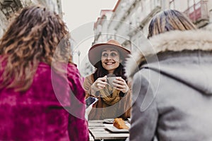 Three women friends having coffee in a terrace in Oporto, Portugal. Having a fun conversation. Lifestyle, tourism and holidays