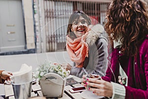 Three women friends having coffee in a terrace in Oporto, Portugal. Having a fun conversation. Lifestyle, tourism and holidays